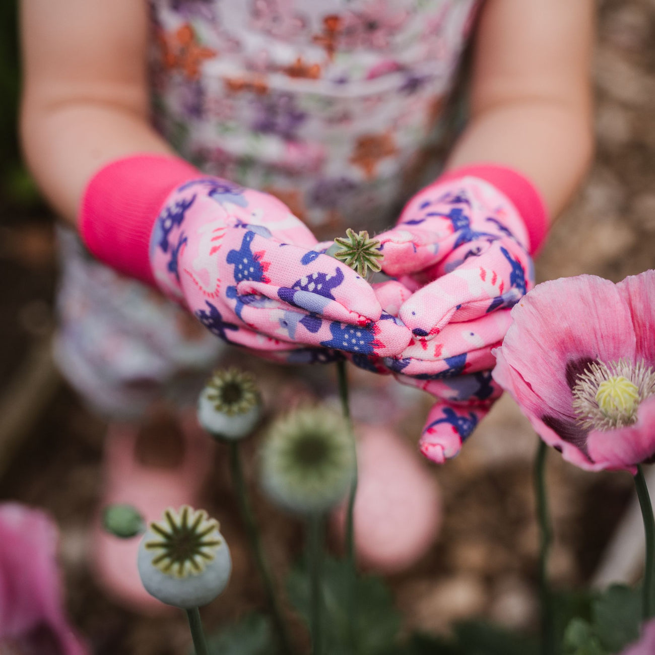 girl with pink gloves on holding flower